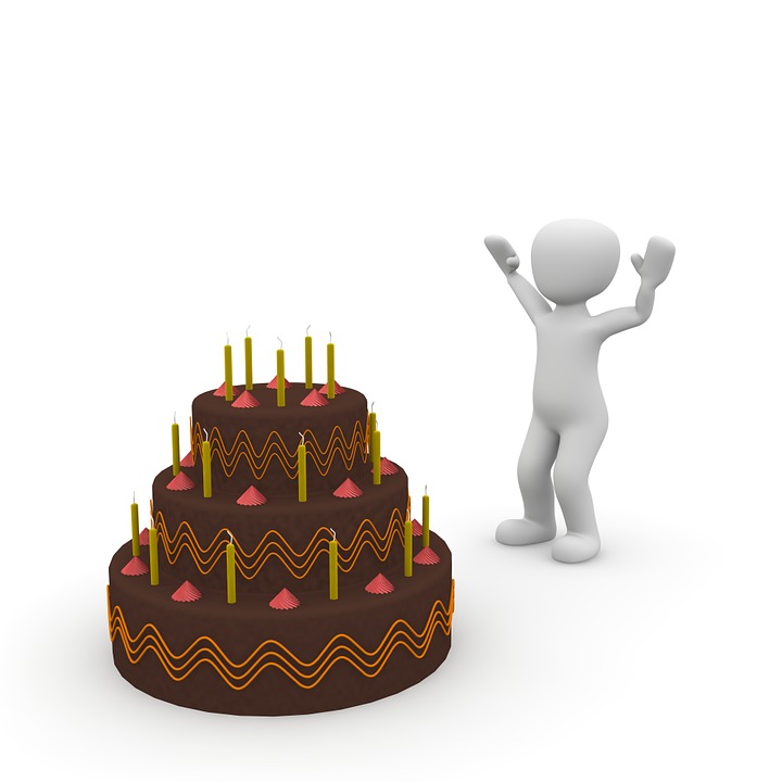 A person standing next to a cake with candles on it.