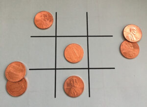 A tic tac toe game with pennies on the board.